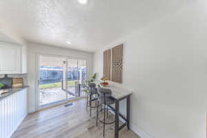 Dining space featuring light wood-style floors, a textured ceiling, and recessed lighting