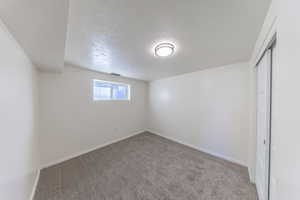 Unfurnished bedroom featuring a textured ceiling, carpet flooring, and a closet