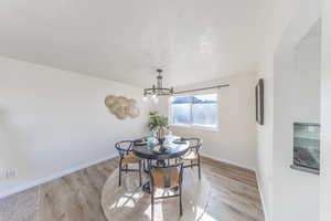 Dining area featuring light wood-style floors, a chandelier, and a textured ceiling