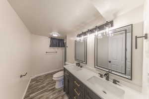 Bathroom with dark wood-type flooring, double vanity, curtained shower, and a textured ceiling