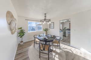 Dining space featuring a textured ceiling, light wood-type flooring, and a chandelier