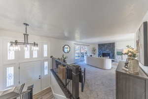 Entrance foyer with a fireplace, a textured ceiling, and light carpet