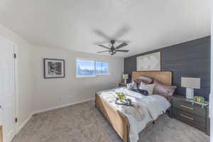 Bedroom featuring an accent wall, light colored carpet, and ceiling fan