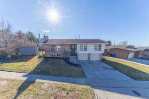 Single story home featuring a front lawn, brick siding, driveway, a chimney, and a garage