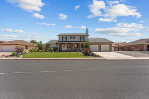 Traditional home featuring covered porch, a front yard, concrete driveway, a chimney, and brick siding