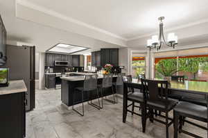 Kitchen with light marble finish flooring, a kitchen breakfast bar, hanging light fixtures, stainless steel appliances, and a peninsula