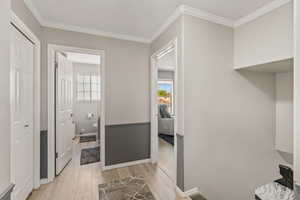 Hallway with crown molding and light wood finished floors