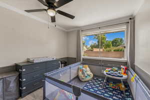 Bedroom featuring light wood finished floors, crown molding, and ceiling fan