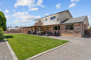 Rear view of house featuring a patio area, brick siding, a fenced backyard, a shingled roof, and a balcony
