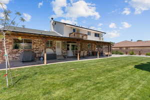 Rear view of property featuring a patio area, brick siding, a chimney, a yard, and a balcony