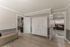Living area with light wood-style flooring and crown molding