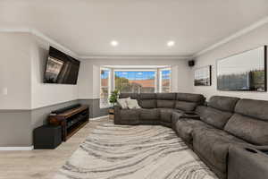 Living area featuring crown molding, light wood-style flooring, and recessed lighting