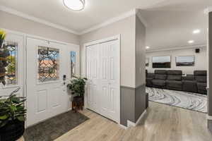 Foyer with crown molding and light wood finished floors