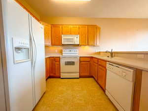 Kitchen featuring white appliances, light countertops, brown cabinets, and a peninsula