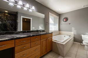 Full bathroom with a tub with jets, vanity, and light tile patterned floors