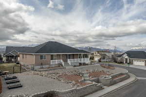 View of front of house with covered porch, a mountain view, roof with shingles, brick siding, and a residential view