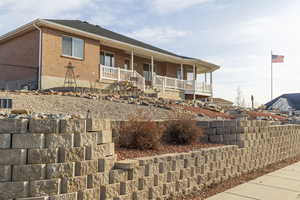 Back of property with a porch, brick siding, and roof with shingles