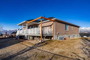 Rear view of property with a lawn, a deck with mountain view, and brick siding