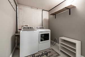 Laundry room featuring washer and dryer, finished concrete floors, and a textured ceiling