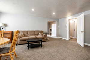 Living room with carpet, recessed lighting, and a textured ceiling