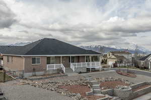 View of front of house with a mountain view, a shingled roof, brick siding, and covered porch