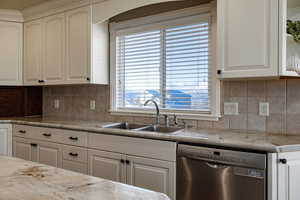 Kitchen featuring white cabinetry, dishwasher, and decorative backsplash