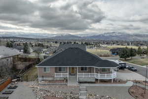 View of front of house with a porch, brick siding, roof with shingles, a residential view, and a mountain view