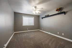 Spare room featuring ceiling fan, dark carpet, and a textured ceiling