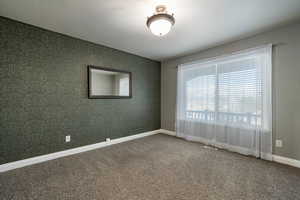 Carpeted spare room featuring wallpapered walls and a textured ceiling