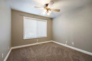 Unfurnished room featuring dark carpet and a ceiling fan