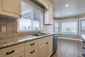 Kitchen with tasteful backsplash, light tile patterned floors, dishwasher, light countertops, and recessed lighting