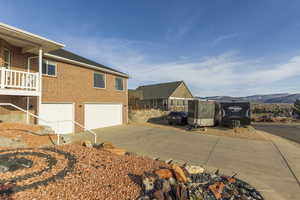 View of property exterior with concrete driveway, brick siding, and a garage