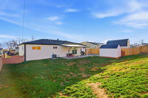 Rear view of house with a storage unit, a fenced backyard, and a patio area