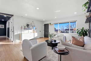 Living room featuring light wood-style floors, a textured ceiling, and recessed lighting