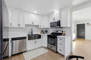 Kitchen with stainless steel appliances, white cabinetry, light wood finished floors, and recessed lighting