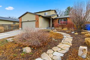 View of front of home featuring driveway, a garage, stucco siding, and brick siding