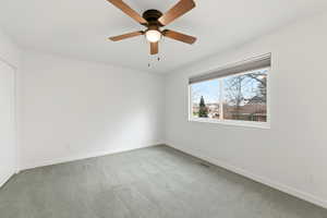 Carpeted empty room featuring baseboards and a ceiling fan