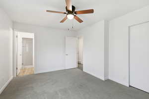 Unfurnished bedroom with carpet floors, ceiling fan, and ensuite bath