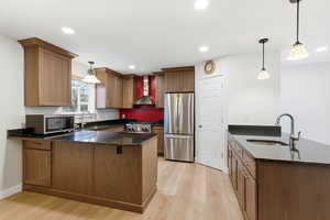 Kitchen with a peninsula, dark stone countertops, stainless steel appliances, hanging light fixtures, and recessed lighting