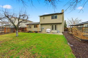 Back of house with a vegetable garden, french doors, a fenced backyard, a patio, and a chimney