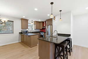 Kitchen featuring a peninsula, a breakfast bar, dark stone counters, brown cabinetry, and recessed lighting