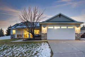 View of front of home with stone siding, driveway, and stucco siding