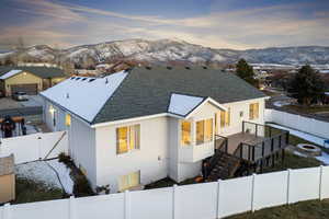 Back of property at dusk featuring a fenced backyard, a shingled roof, stucco siding, a fire pit, and a gate