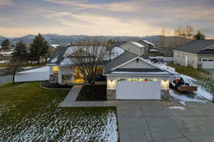 View of front of property with stone siding, stucco siding, driveway, a mountain view, and a garage