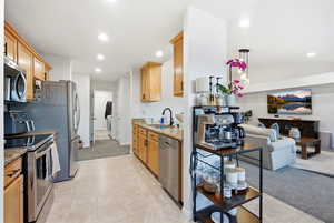 Kitchen featuring appliances with stainless steel finishes, light stone counters, light colored carpet, recessed lighting, and light tile patterned flooring