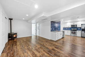 Kitchen with white cabinets, a wood stove, stainless steel appliances, recessed lighting, and light countertops