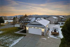 View of front facade with concrete driveway, stucco siding, stone siding, a garage, and a mountain view