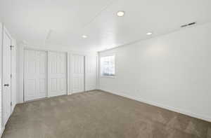 Unfurnished bedroom featuring two closets, carpet floors, and recessed lighting