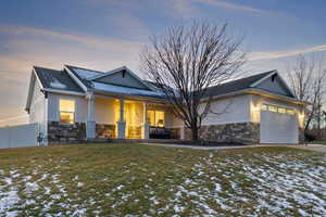 View of front of house with stone siding, stucco siding, a garage, and covered porch