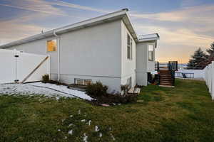 Property exterior at dusk featuring stucco siding, stairs, and a gate